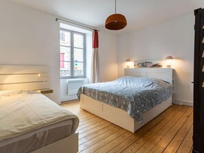 Een slaapkamer met een bed, een raam, een radiator en een hanglamp.