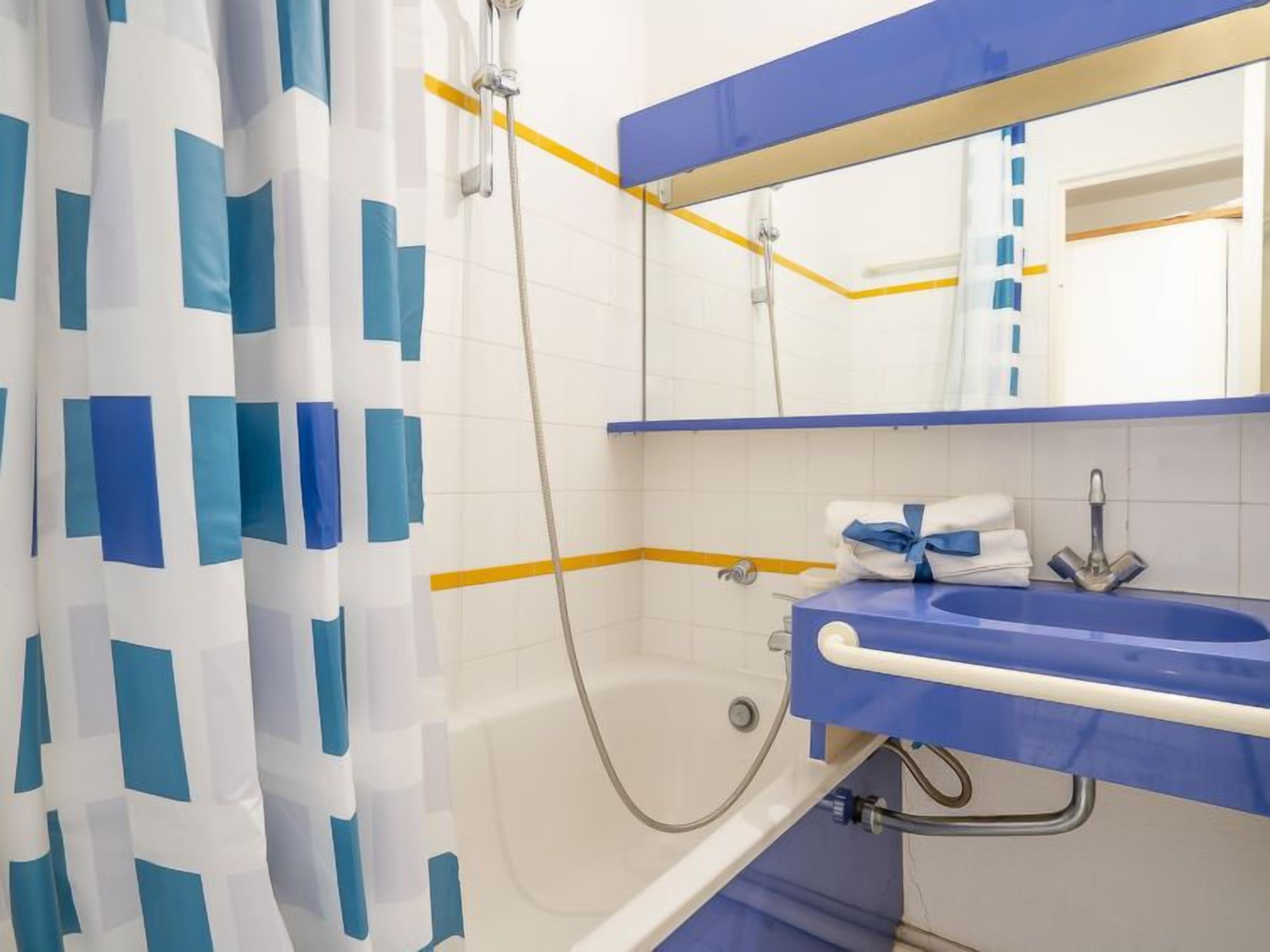 A bathroom with a shower, a sink, and a mirror.