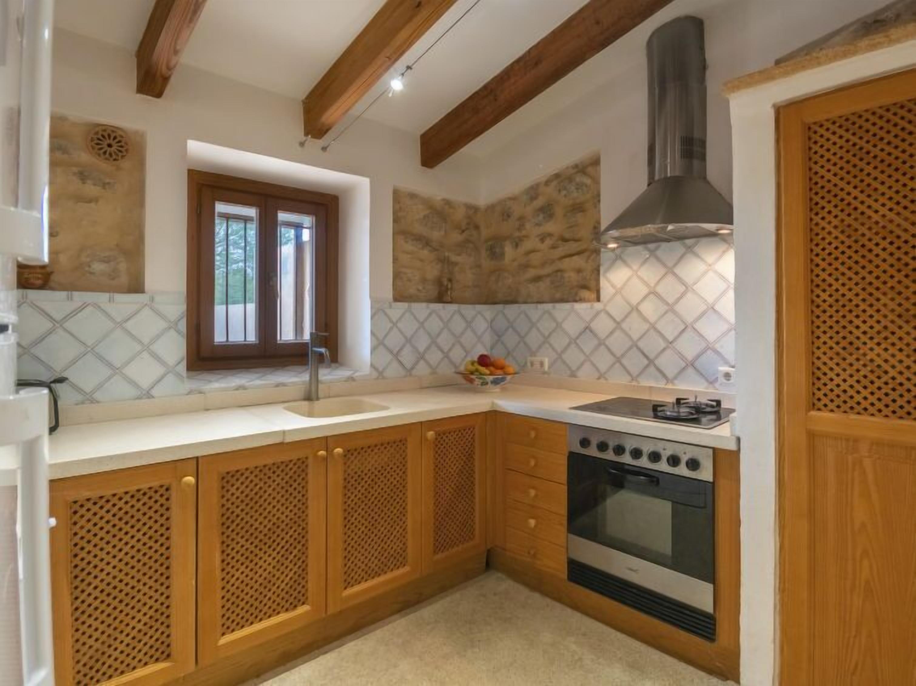 Une cuisine de taille réduite, dotée de meubles en bois, d’un four encastré et d’une fenêtre.