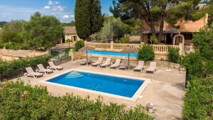 A swimming pool with lounge chairs, surrounded by greenery and traditional architecture. - Capella Rubi by Interhome (Artà)