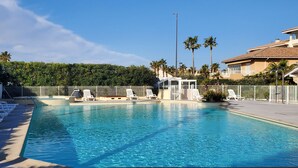Een zwembad met ligbedden en een klein poolhuis.