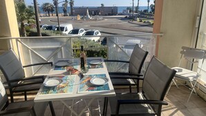 Een balkon met een eettafel, stoelen en een fles wijn.