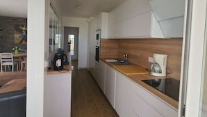 Een moderne keuken met witte kastjes, een houten aanrecht en een koffiezetapparaat.