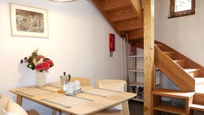 Ein Essbereich mit Holztisch, Stühlen, einem Blumenstrauß, einer Kaffeemaschine und einem gerahmten Bild an der Wand.