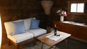 Ein gemütliches Zimmer mit einer Holzdirektiva, einem kleinen Tisch mit einer Flasche und einem Glas sowie einem Fenster, über dem eine Korb hängt.