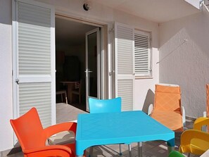 Een terras met een tafel en stoelen, een schuifdeur en uitzicht op het interieur.