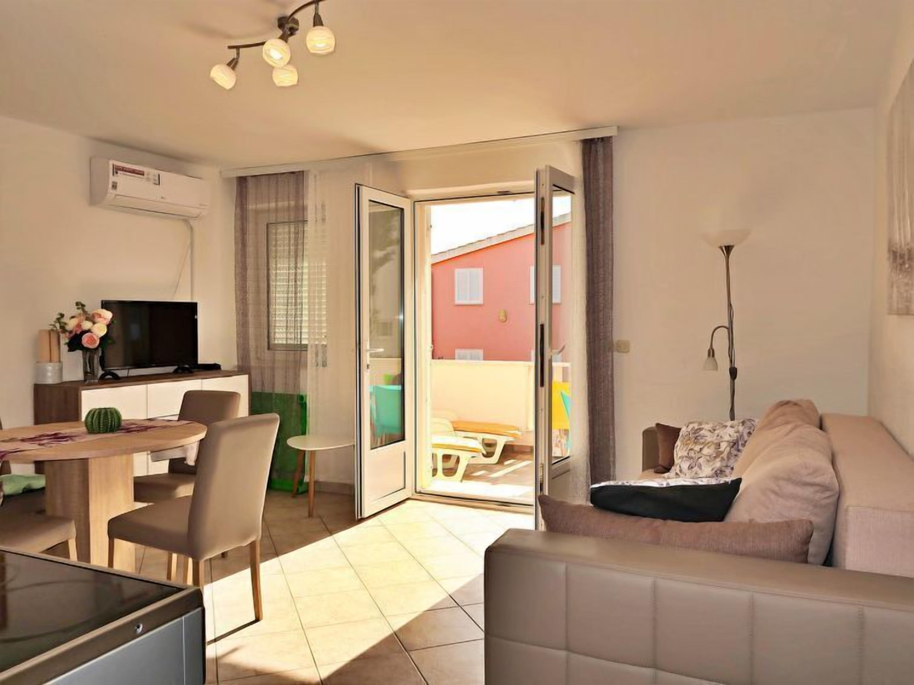 A modern living room with a sofa, a TV, and a dining area with a table and chairs.