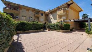 A multi-story residential building with balconies, a tiled courtyard, and surrounding greenery. - Port FREJUS Studio with sleeping area of ​​30 m2 for 2 Adults 2 Children with quiet balcony on the garden side (Fréjus)