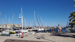 A marina with numerous boats docked, a clear blue sky, and a building in the background. - Port FREJUS Studio with sleeping area of ​​30 m2 for 2 Adults 2 Children with quiet balcony on the garden side (Fréjus)