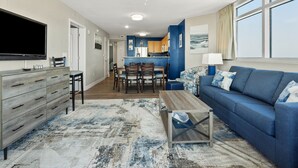 A modern living room with a blue sofa, wooden coffee table, and a flat-screen TV. - Premier Resort: Oceanfront w/Amenities, Restaurants & Amazing Views-North Myrtle Beach (North Myrtle Beach)