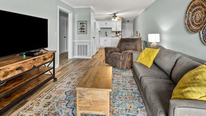 Un salon doté d’un téléviseur à écran plat, d’un canapé en cuir marron, d’une table basse en bois et d’un tapis à motifs.