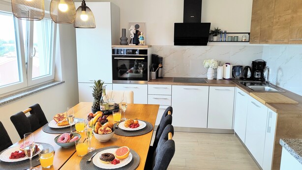 A modern kitchen with white cabinets, a wooden countertop, and a built-in oven.