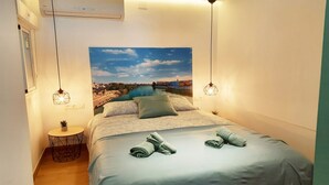 A bedroom with a bed, two bedside lamps, a small round table with a plant, and a wall-mounted air conditioner. - Lovely penthouse apartment with terrace Lovely Center Apartments Alameda (Sevilla)
