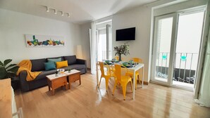 A living room with a sofa, coffee table, and dining table with chairs. There is a TV mounted on the wall and a balcony with a view. - Lovely penthouse apartment with terrace Lovely Center Apartments Alameda (Sevilla)