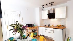A modern kitchen with white cabinets, a microwave, and a sink. There is a dining table with blue and yellow plates and a vase with flowers. - Lovely penthouse apartment with terrace Lovely Center Apartments Alameda (Sevilla)