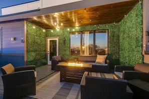 An outdoor seating area with a fire feature, a wooden ceiling, and a green wall.
