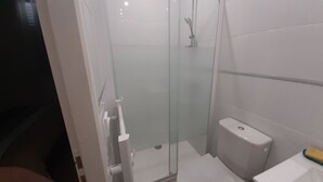 Une salle de bain avec une douche à parois de verre, des toilettes et un lavabo.