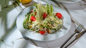 A plate of salad with lettuce, tomatoes, and croutons on a marble table. - King Solomon Hotel Batumi (Batumi)