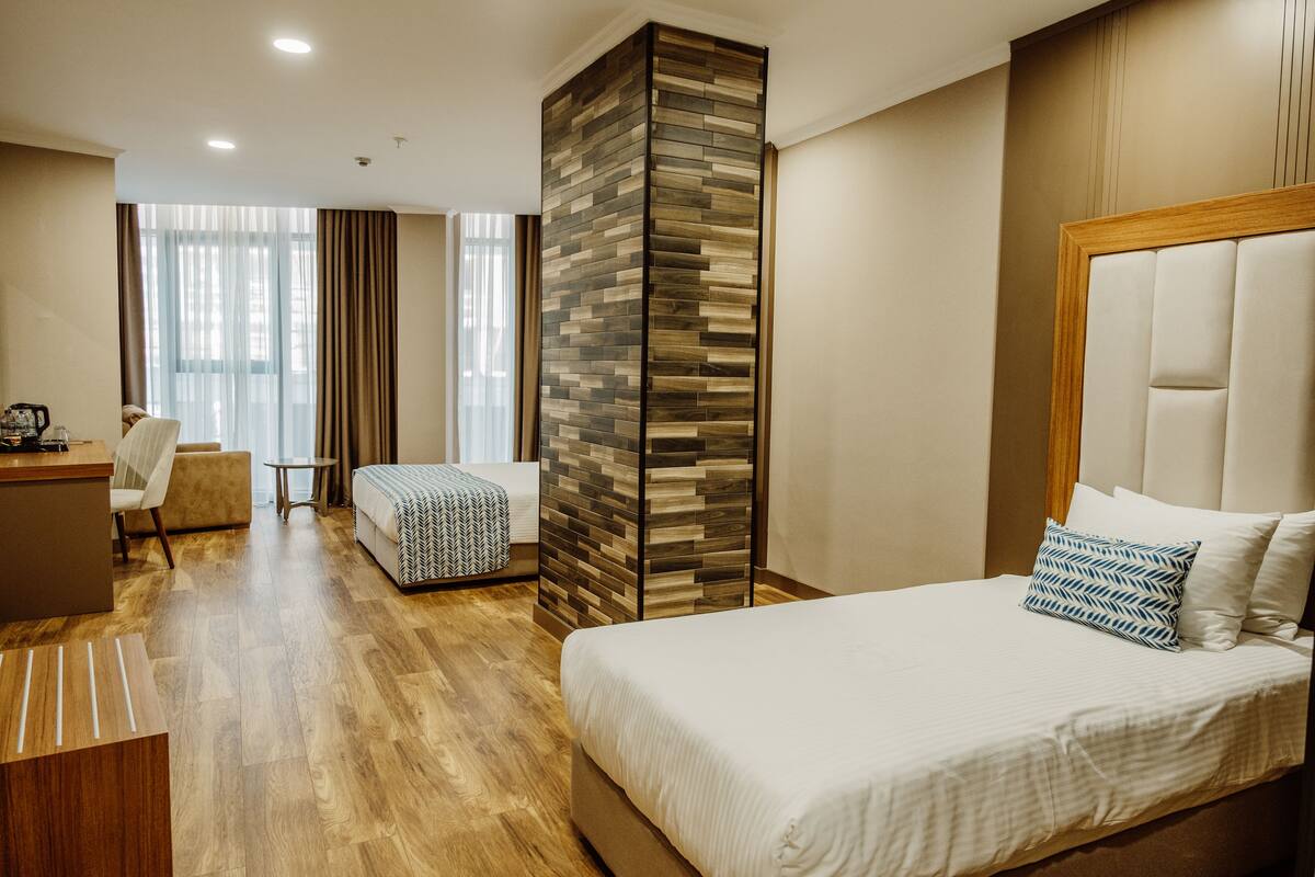 Ein Hotelzimmer mit einem großen Bett, einem Schreibtisch, einer Couch und einer Wand aus Holz.