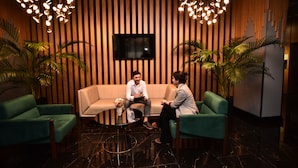 A modern lounge area with a sofa, two green armchairs, a small table with a vase, and potted plants. - King Solomon Hotel Batumi (Batumi)