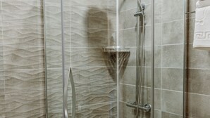 A glass-enclosed shower with a curved design, a handheld showerhead, and a wall-mounted faucet. - King Solomon Hotel Batumi (Batumi)