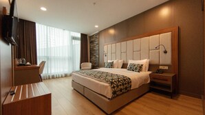A hotel room with a large bed, a desk, a chair, and a TV on the wall. - King Solomon Hotel Batumi (Batumi)