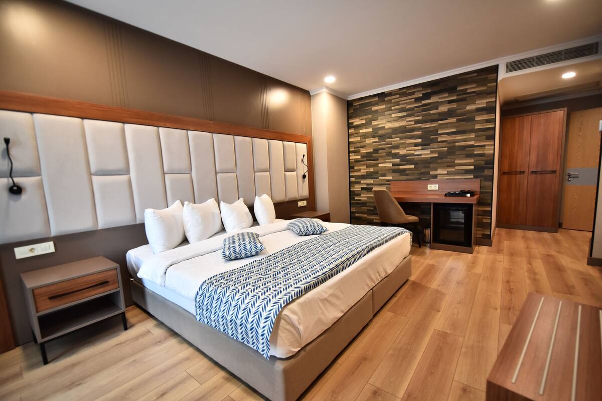 Ein modernes Schlafzimmer mit einem großen Bett, Nachttischen, einem Schreibtisch und einem Kleiderschrank.