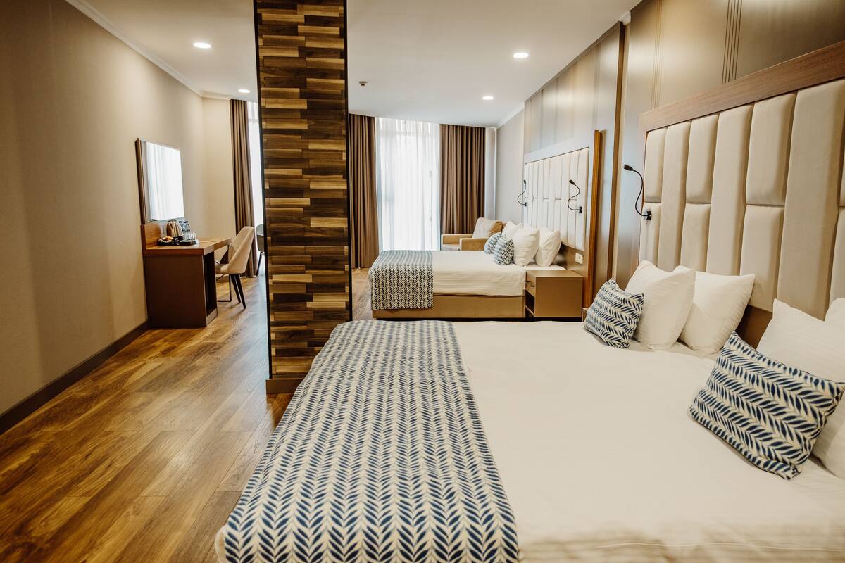 Ein modernes Hotelzimmer mit einem großen Bett, einem Schreibtisch, einem Stuhl und einem Kleiderschrank.