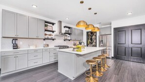 Una cocina moderna con armarios grises, una isla central con taburetes y electrodomésticos de acero inoxidable.