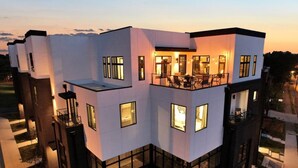 Un edificio de varios pisos con balcones, ventanas amplias y una terraza en la azotea.
