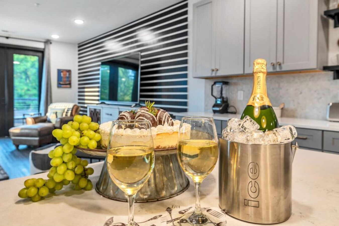 Una cucina moderna con zona pranzo, una bottiglia di champagne, ghiaccio e bicchieri.