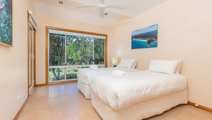 Una camera da letto con un'ampia finestra, un letto e una ventola a soffitto.