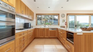 Una cucina moderna con mobili in legno, elettrodomestici in acciaio inox, un'ampia finestra e vista sull'esterno.