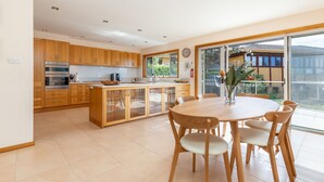 Una cucina moderna con mobili in legno, un'isola centrale con vetrate e un'area pranzo con un tavolo rotondo e sedie.