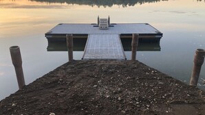 A dock extending into calm water with a wooden structure at the end. - Private Lake Front with boat launch and dock. (Kenai)