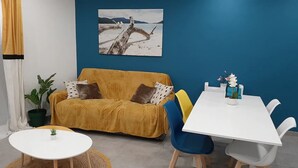 Una habitación con un sofá amarillo, una mesa blanca y una pared azul.