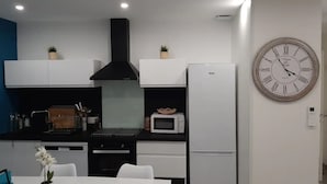 Una cocina moderna con armarios blancos, una campana extractora negra, un microondas y un reloj de pared grande.