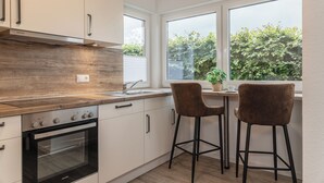 Eine moderne Küche mit Backofen, Edelstahl-Dunstabzugshaube und Blick auf Grünflächen.