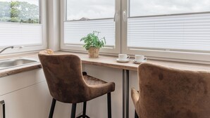Eine Küche mit Fenster, zwei Stühlen, einem Spülbecken und einem Blumentopf.