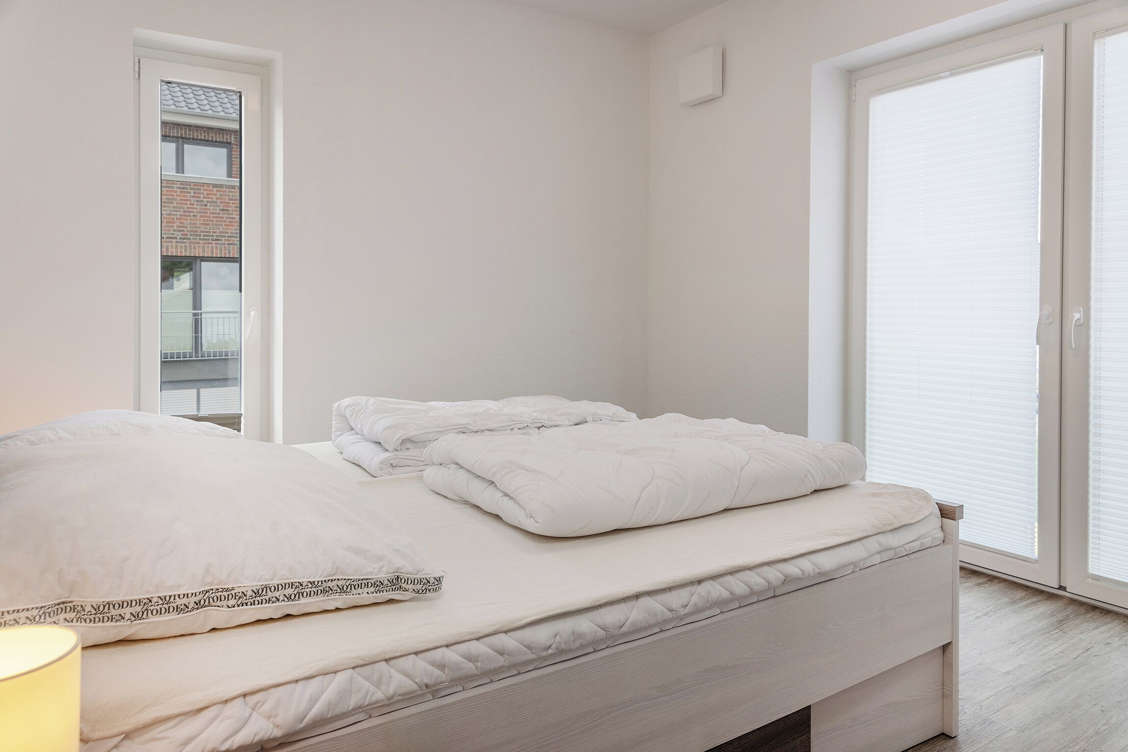 Une chambre à coucher au style minimaliste, avec un lit, une fenêtre et une porte.