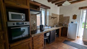 Eine Küche mit Holzausstattung, einer integrierten Mikrowelle, einem Backofen, einer Kaffeemaschine und einem Kühlschrank.