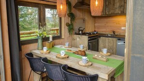 A cozy wooden cabin with a dining area featuring a table set with cups, a vase with flowers, and a view of the outdoors. - EuroParcs Ruinen (Ruinen)