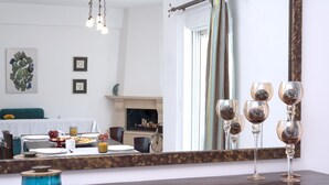 A dining area with a wooden table set for breakfast, a mirror reflecting the room, and a blue candle on a dresser. - Haris Villas (Viannos)