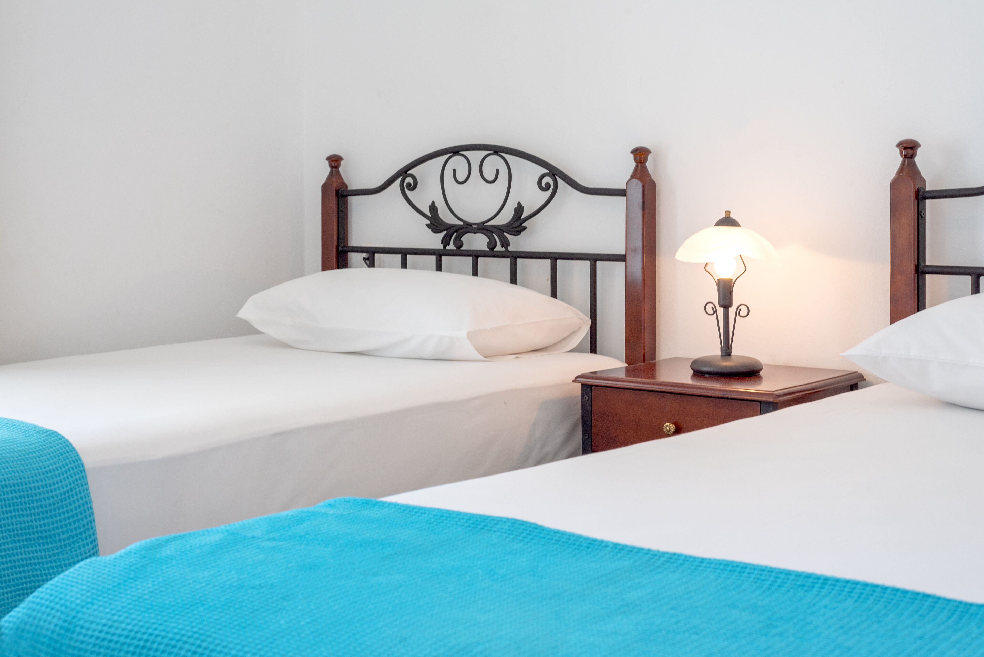 Ein Doppelbett mit Holz-Kopfteil, ein Nachttisch mit Lampe und eine blaue Decke.