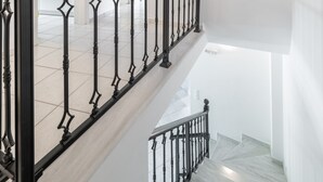 A staircase with a black metal railing and a light-colored floor. - Haris Villas (Viannos)