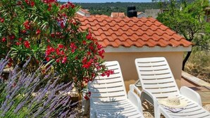 Una terraza con sillones blancos y techo de tejas rojas.
