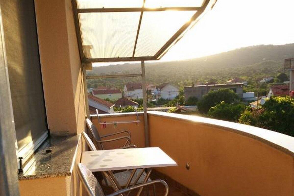 Un balcon avec une table et des chaises, une vue sur un quartier résidentiel et un immeuble en arrière-plan.