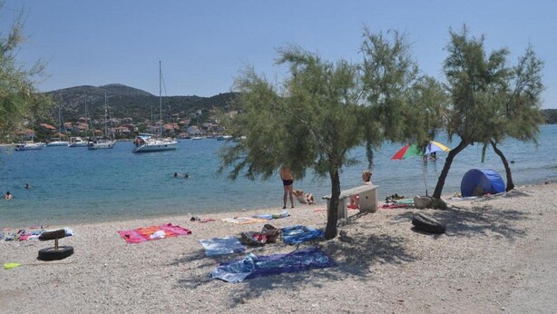 Una playa con barcos, una carpa y gente relajándose.
