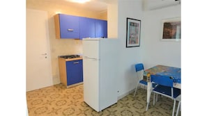 Cozy kitchen area with a refrigerator, stove, and dining space with a table and chairs.