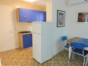 Frigorífico, placa de cocina, utensilios de cocina y mesa de comedor